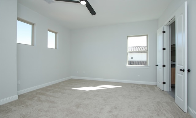 empty room with a healthy amount of sunlight, ceiling fan, and light colored carpet