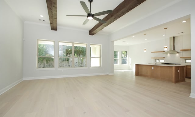 unfurnished living room with beamed ceiling, sink, light hardwood / wood-style flooring, crown molding, and ceiling fan