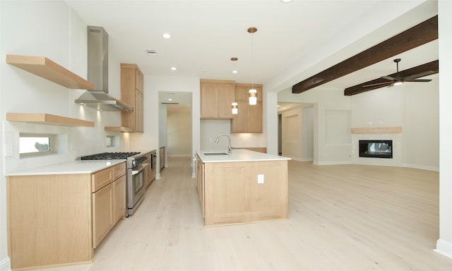 kitchen with high end stove, beam ceiling, decorative light fixtures, sink, and wall chimney range hood