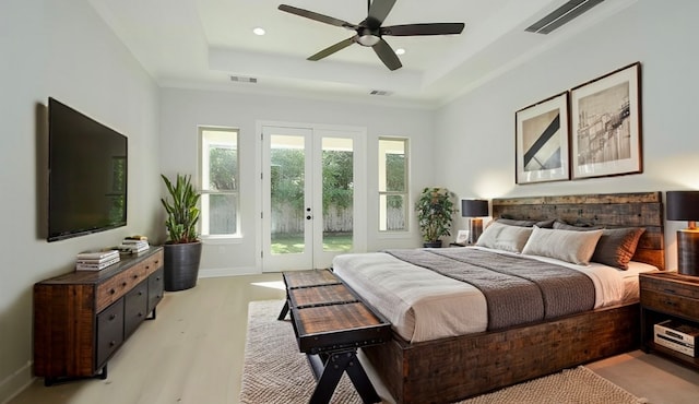 bedroom with ceiling fan, a tray ceiling, french doors, and access to exterior