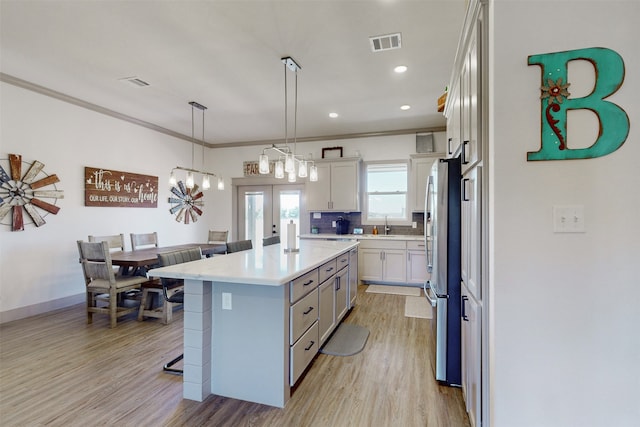 kitchen featuring ornamental molding, a kitchen island, french doors, white cabinetry, and a breakfast bar