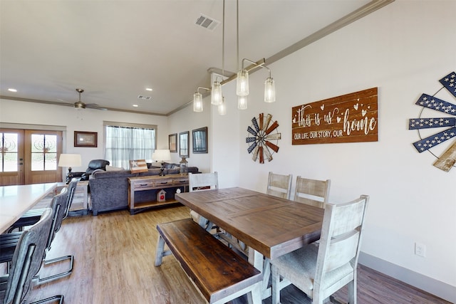 dining space featuring ceiling fan, french doors, crown molding, and light hardwood / wood-style floors