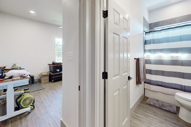 bathroom with hardwood / wood-style flooring, toilet, and a shower with shower curtain