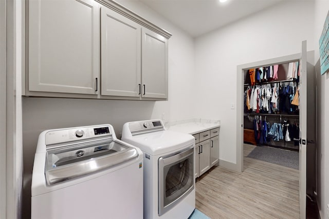 laundry room with cabinets, light wood-type flooring, and washer and dryer