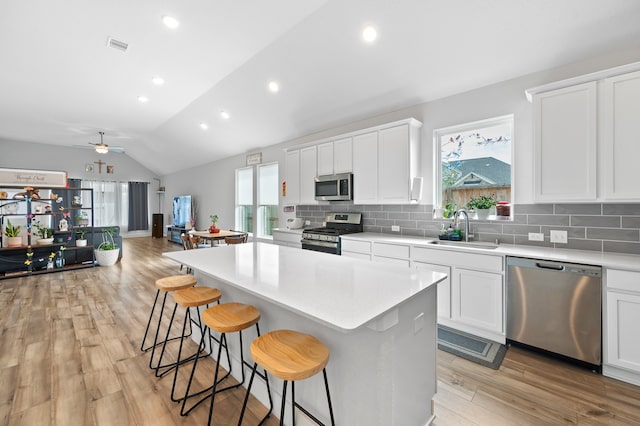 kitchen with vaulted ceiling, appliances with stainless steel finishes, sink, and a wealth of natural light