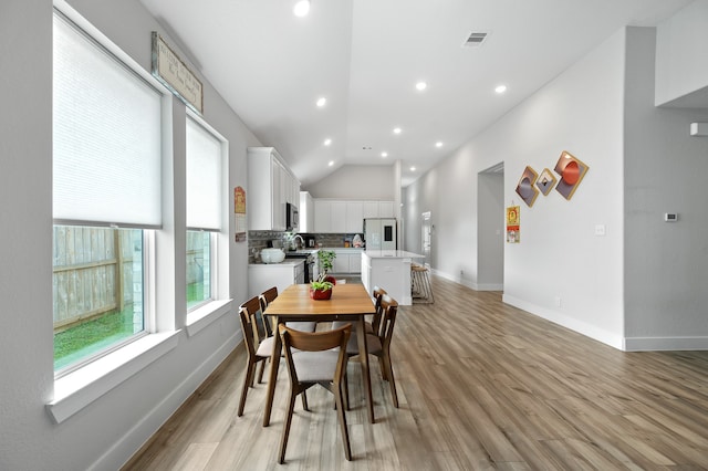 dining room with light wood-type flooring and lofted ceiling