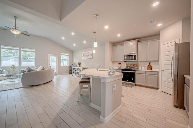 kitchen featuring stainless steel appliances, ceiling fan, light wood-type flooring, and a center island with sink