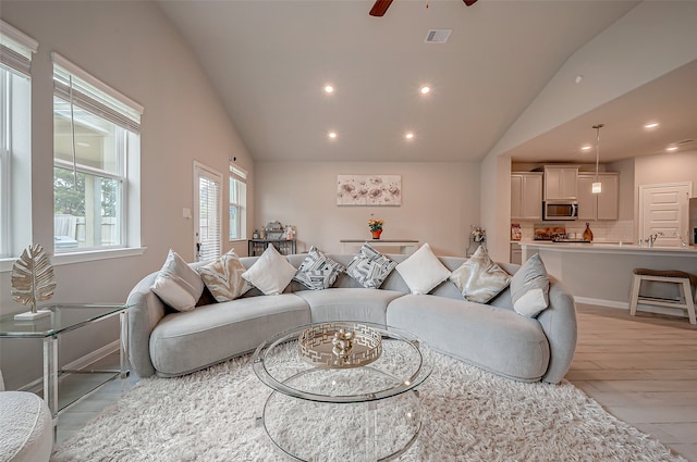 living room with light wood-type flooring, lofted ceiling, and ceiling fan