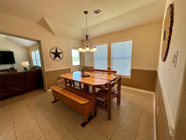 tiled dining space with vaulted ceiling and an inviting chandelier