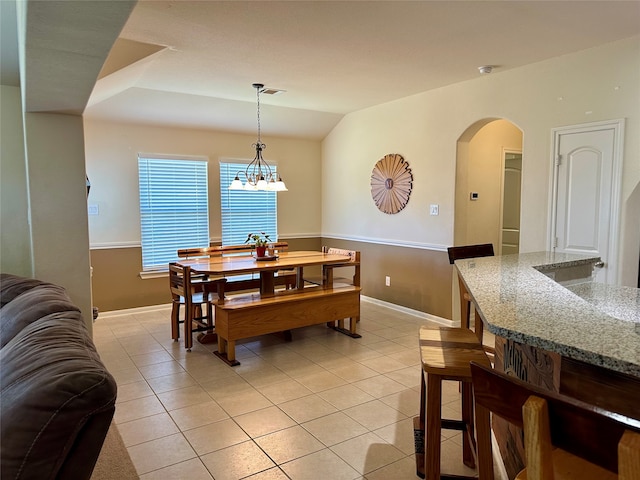 tiled dining room with lofted ceiling and a chandelier