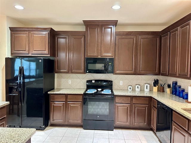 kitchen with light stone countertops, black appliances, light tile patterned floors, and tasteful backsplash