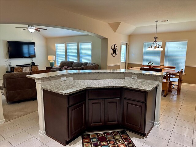 kitchen featuring ceiling fan with notable chandelier, lofted ceiling, pendant lighting, and dark brown cabinetry