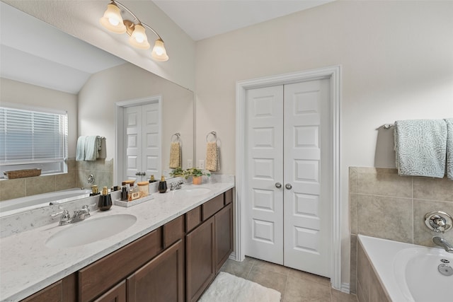 bathroom with tile patterned flooring, lofted ceiling, tiled tub, and vanity