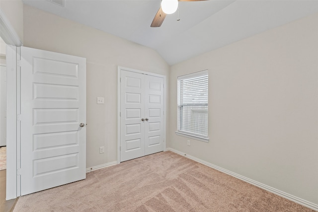 unfurnished bedroom with light carpet, a closet, lofted ceiling, and ceiling fan