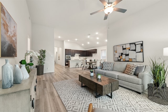 living room featuring light hardwood / wood-style floors, ceiling fan, and high vaulted ceiling