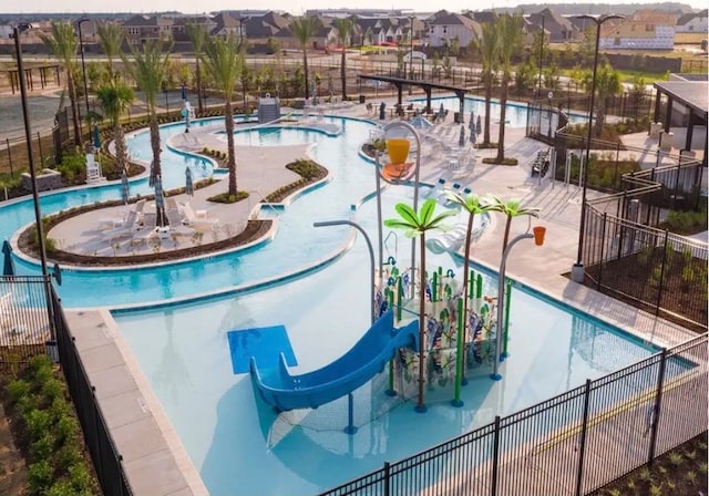 view of swimming pool with a hot tub, a water slide, and a patio