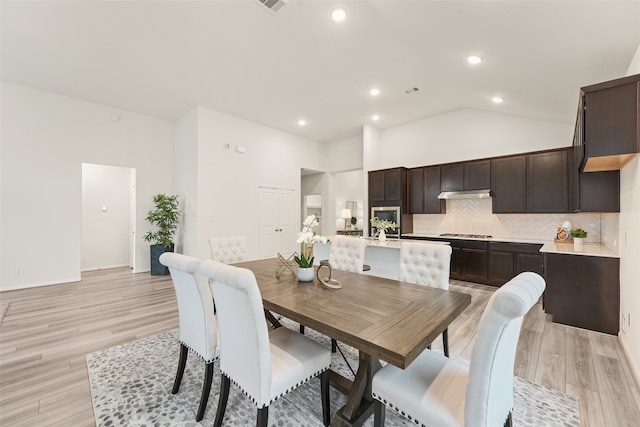 dining area featuring light hardwood / wood-style floors and high vaulted ceiling