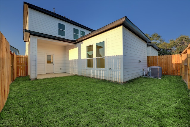 rear view of house with a lawn, central AC unit, and a patio area