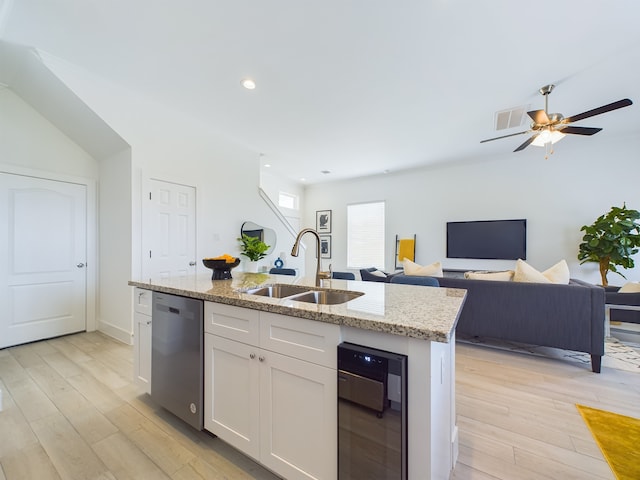 kitchen with an island with sink, sink, light hardwood / wood-style flooring, white cabinetry, and dishwasher