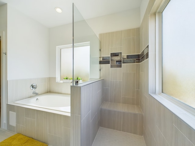 bathroom with tiled tub and a healthy amount of sunlight