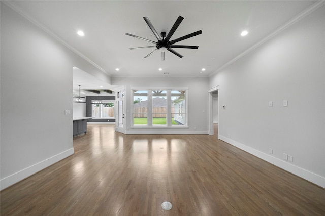 unfurnished living room with ornamental molding, ceiling fan with notable chandelier, and dark wood-type flooring