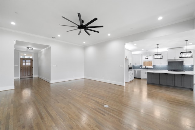 unfurnished living room with ceiling fan, sink, ornamental molding, and hardwood / wood-style flooring