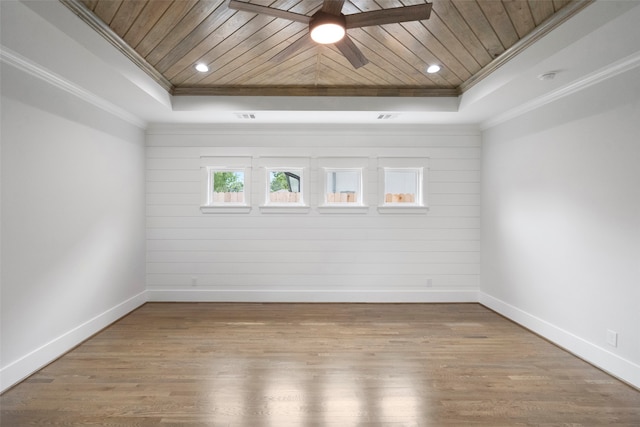 empty room with hardwood / wood-style floors, a raised ceiling, and crown molding