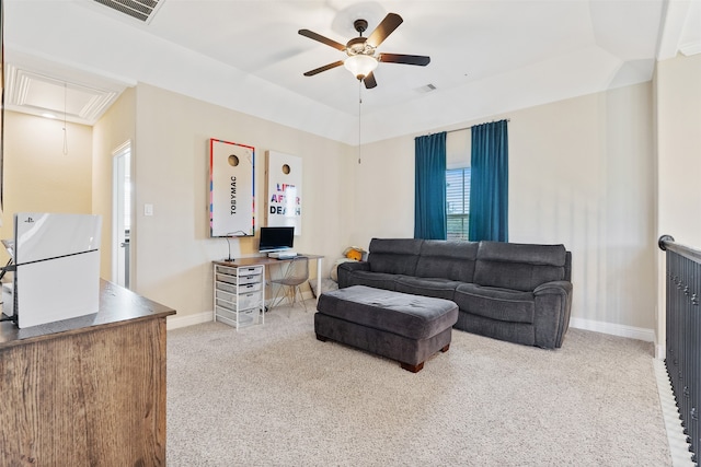 carpeted living room with a tray ceiling and ceiling fan