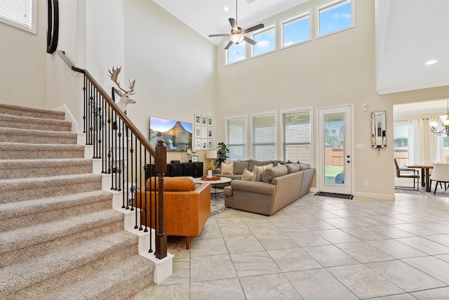 tiled living room with ceiling fan with notable chandelier and a towering ceiling