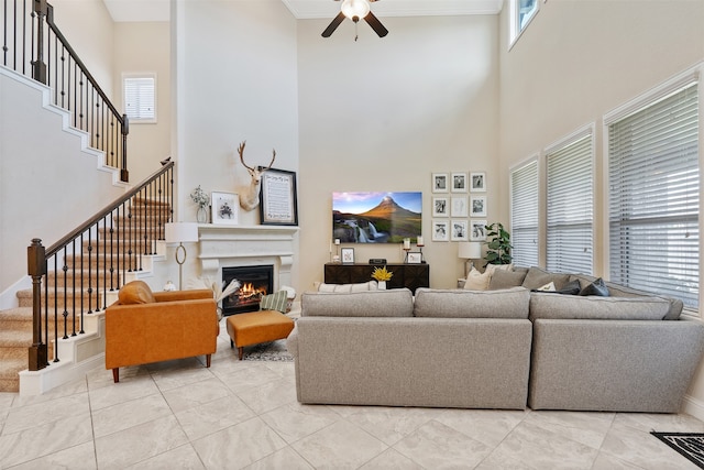 living room with ornamental molding, a towering ceiling, ceiling fan, and plenty of natural light