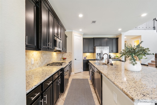 kitchen featuring stainless steel appliances, light stone counters, a kitchen island with sink, and sink