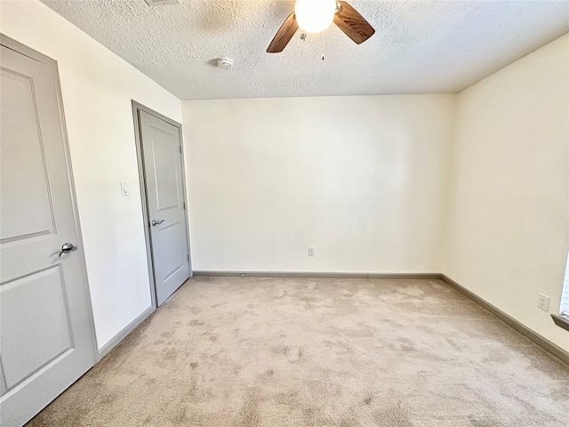 unfurnished bedroom with a textured ceiling, light carpet, and ceiling fan