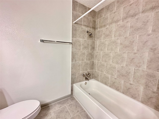 bathroom featuring tile patterned flooring, tiled shower / bath, and toilet