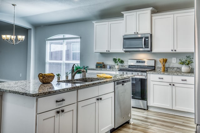 kitchen with a kitchen island with sink, sink, white cabinets, an inviting chandelier, and stainless steel appliances