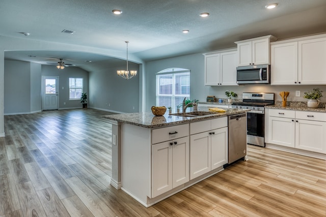 kitchen featuring appliances with stainless steel finishes, lofted ceiling, sink, and white cabinets