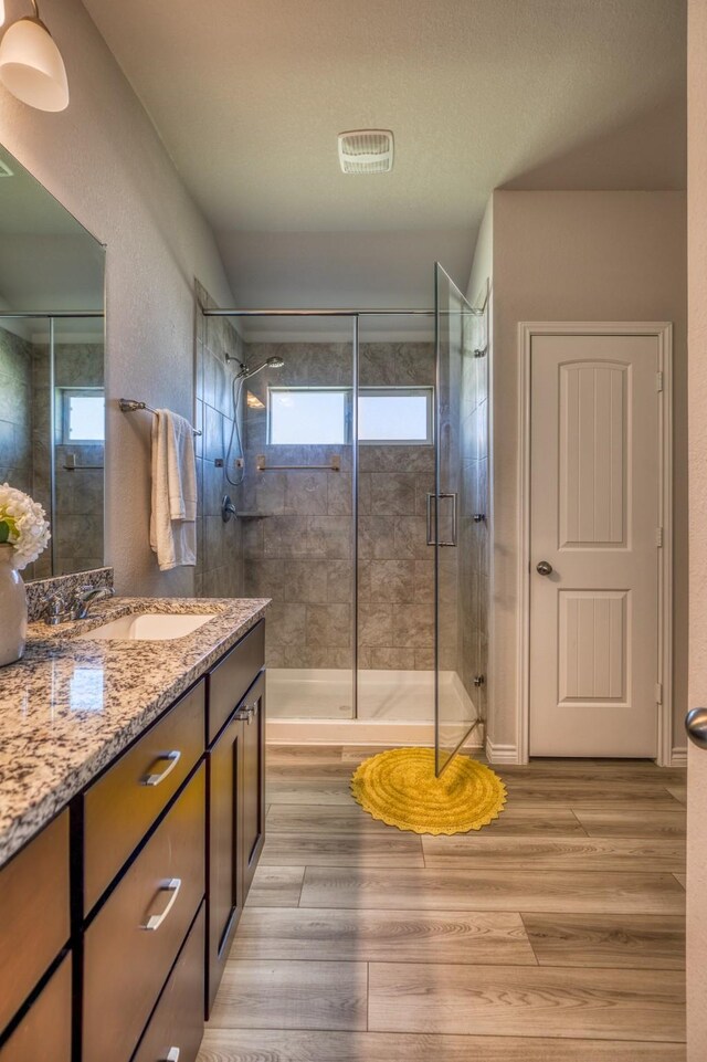 bathroom featuring wood-type flooring, vanity, a textured ceiling, and a shower with door