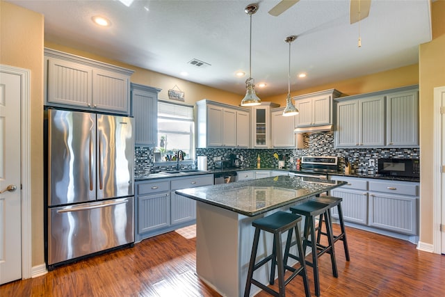 kitchen featuring appliances with stainless steel finishes, hanging light fixtures, a center island, ceiling fan, and sink