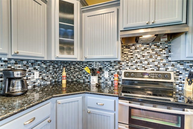 kitchen featuring dark stone countertops, stainless steel electric stove, and backsplash