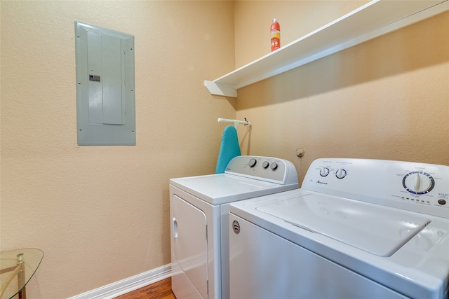 clothes washing area with wood-type flooring, washing machine and dryer, and electric panel