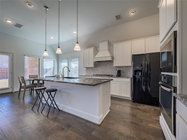 kitchen with dark hardwood / wood-style floors, an island with sink, white cabinets, custom exhaust hood, and appliances with stainless steel finishes