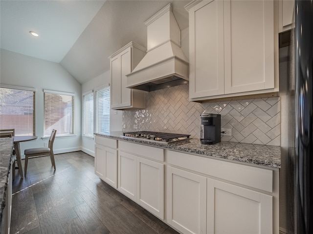 kitchen with white cabinetry, vaulted ceiling, dark wood-type flooring, custom exhaust hood, and black fridge