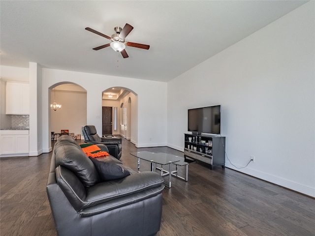 living room featuring ceiling fan with notable chandelier and dark wood-type flooring