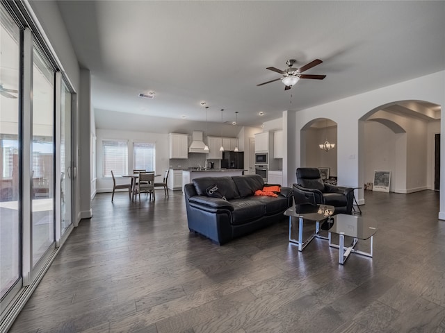 living room with ceiling fan with notable chandelier and dark hardwood / wood-style floors