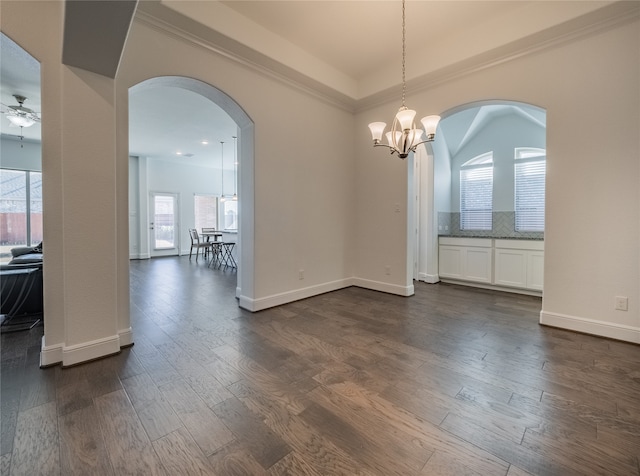 spare room featuring ceiling fan with notable chandelier, ornamental molding, a healthy amount of sunlight, and dark hardwood / wood-style flooring