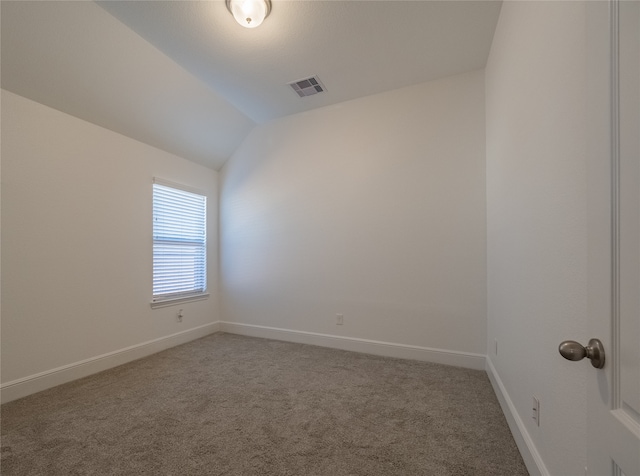 carpeted spare room featuring vaulted ceiling