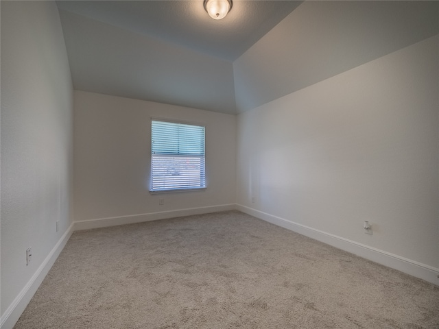 carpeted empty room with lofted ceiling