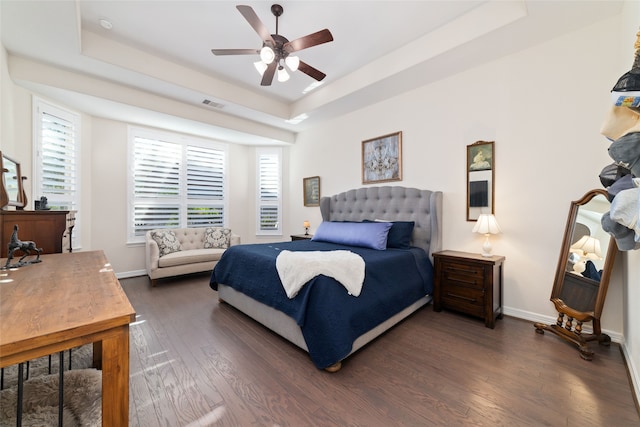 bedroom featuring ceiling fan, dark hardwood / wood-style flooring, and a raised ceiling