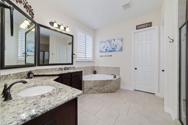 bathroom featuring vanity, tile patterned flooring, and a relaxing tiled tub