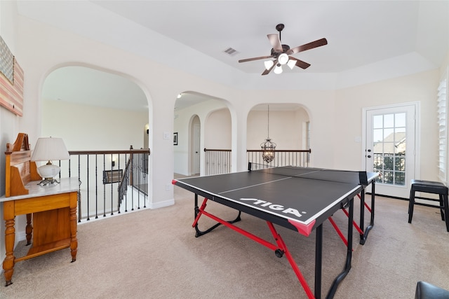 playroom featuring carpet floors, ceiling fan with notable chandelier, and a tray ceiling