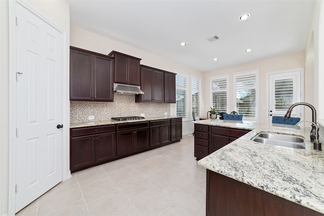 kitchen with sink, dark brown cabinets, stainless steel gas cooktop, and light stone counters